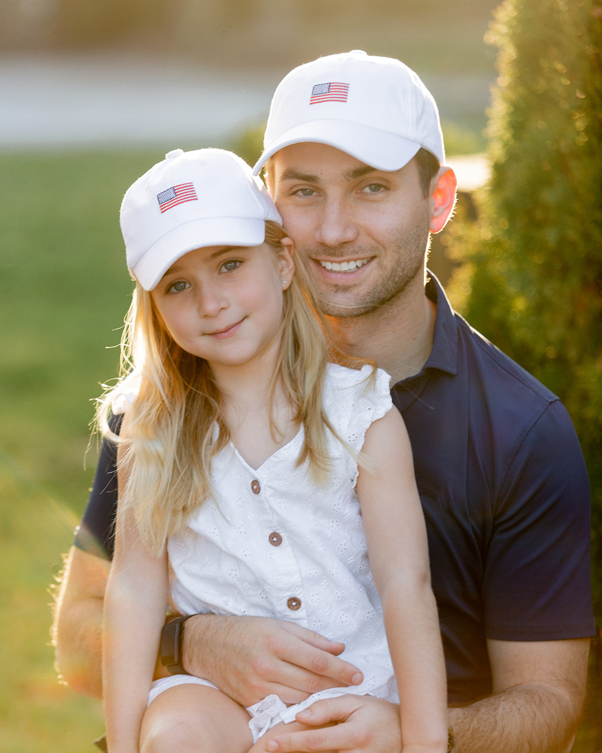 Dad and daughter wearing matching baseball hat with American flag embroidery