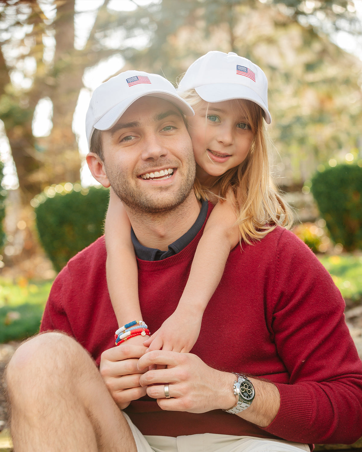 Dad and daughter wearing matching baseball hat with American flag embroidery