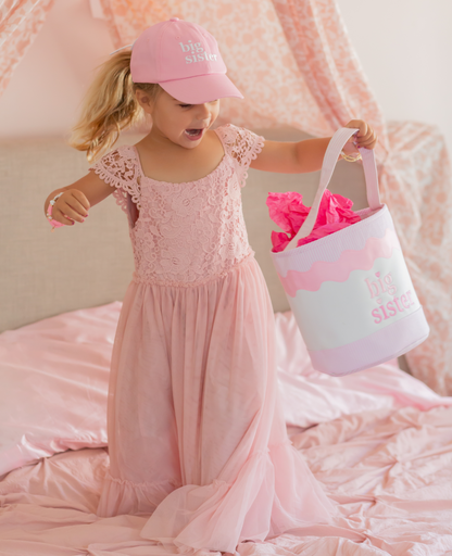 Girl wearing pink big sister hat, big sister bracelet and holding a big sister tote bag