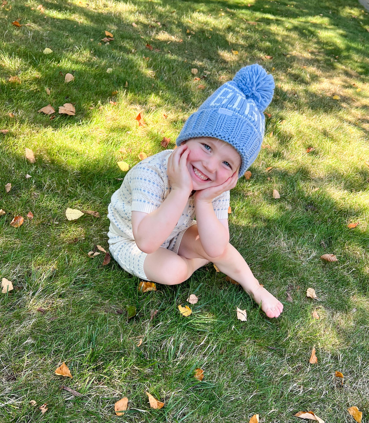 Little boy wearing a "big bro" bobble hat with pom pom