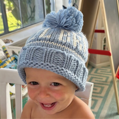 Toddler boy wearing a blue "lil bro" bobble hat