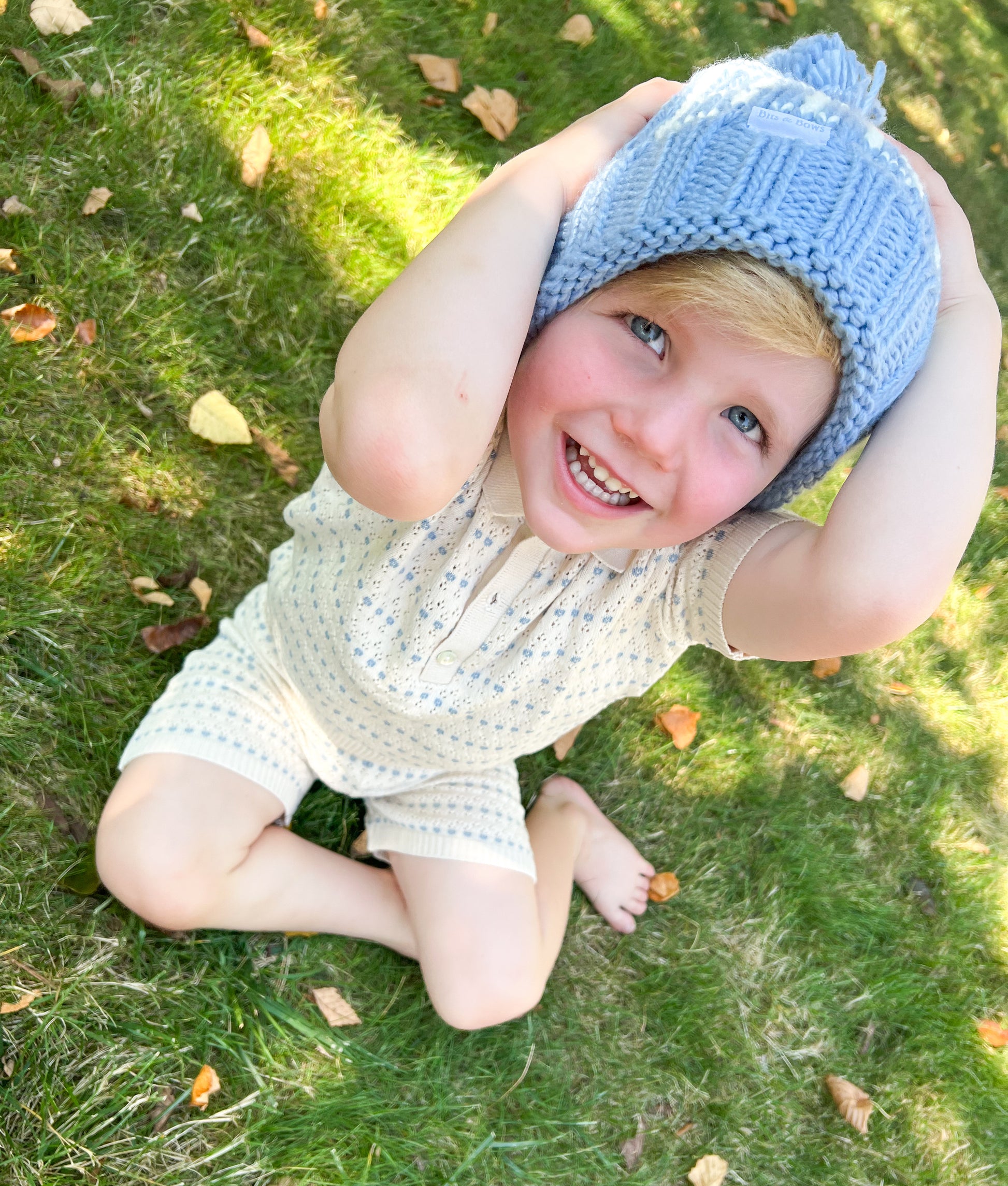 Little boy wearing a blue knit bobble hat with pom pom