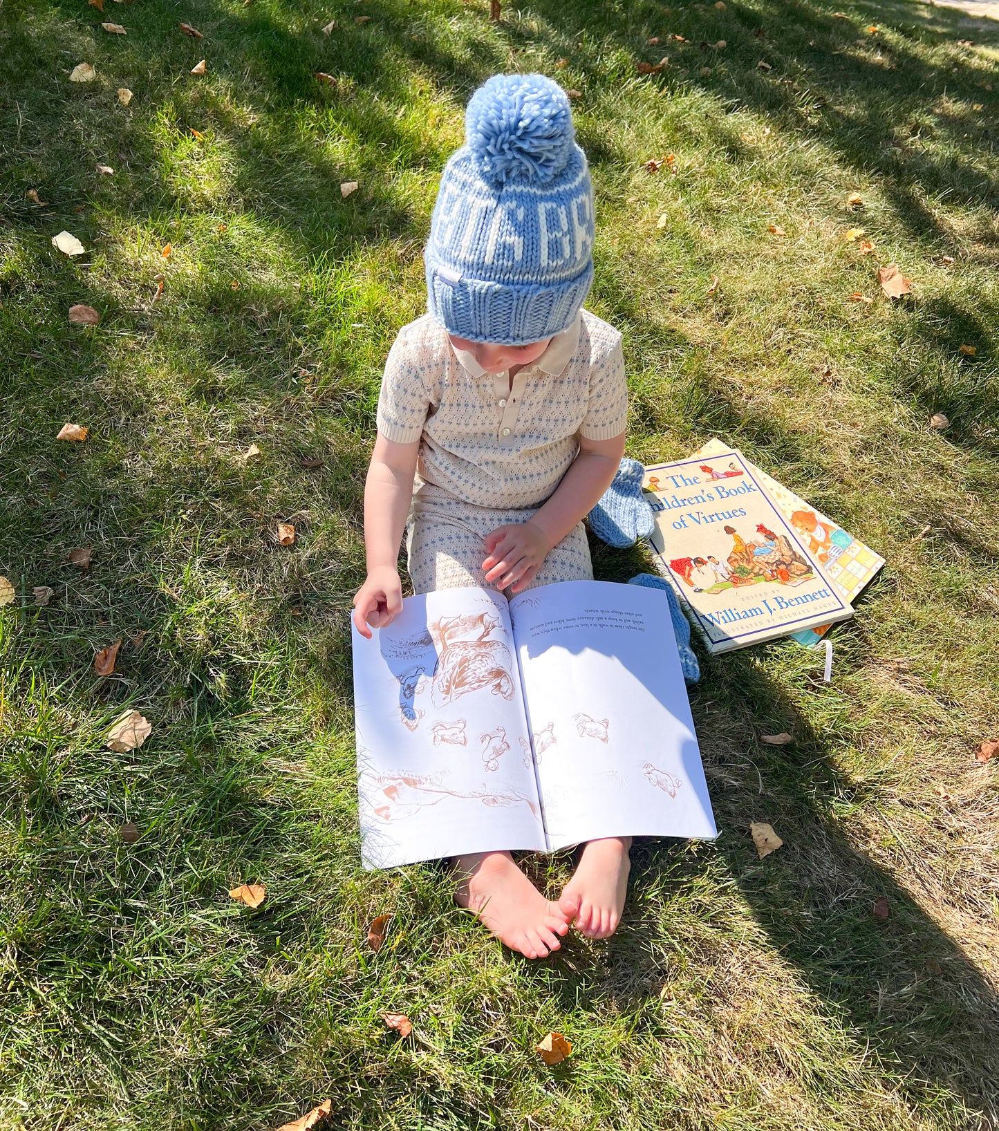 Little boy reading books and wearing a "big bro" bobble hat