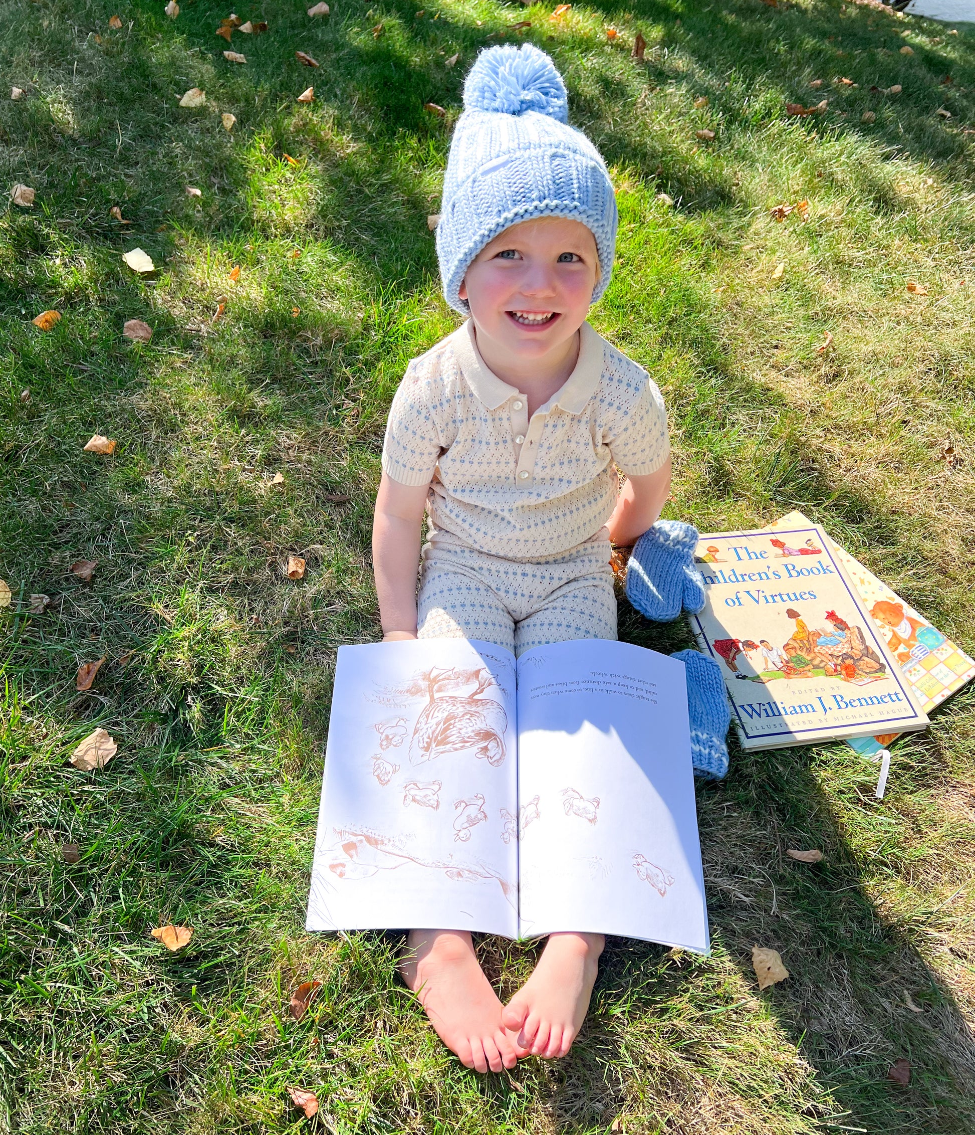 Little boy reading books and wearing a "big bro" bobble hat