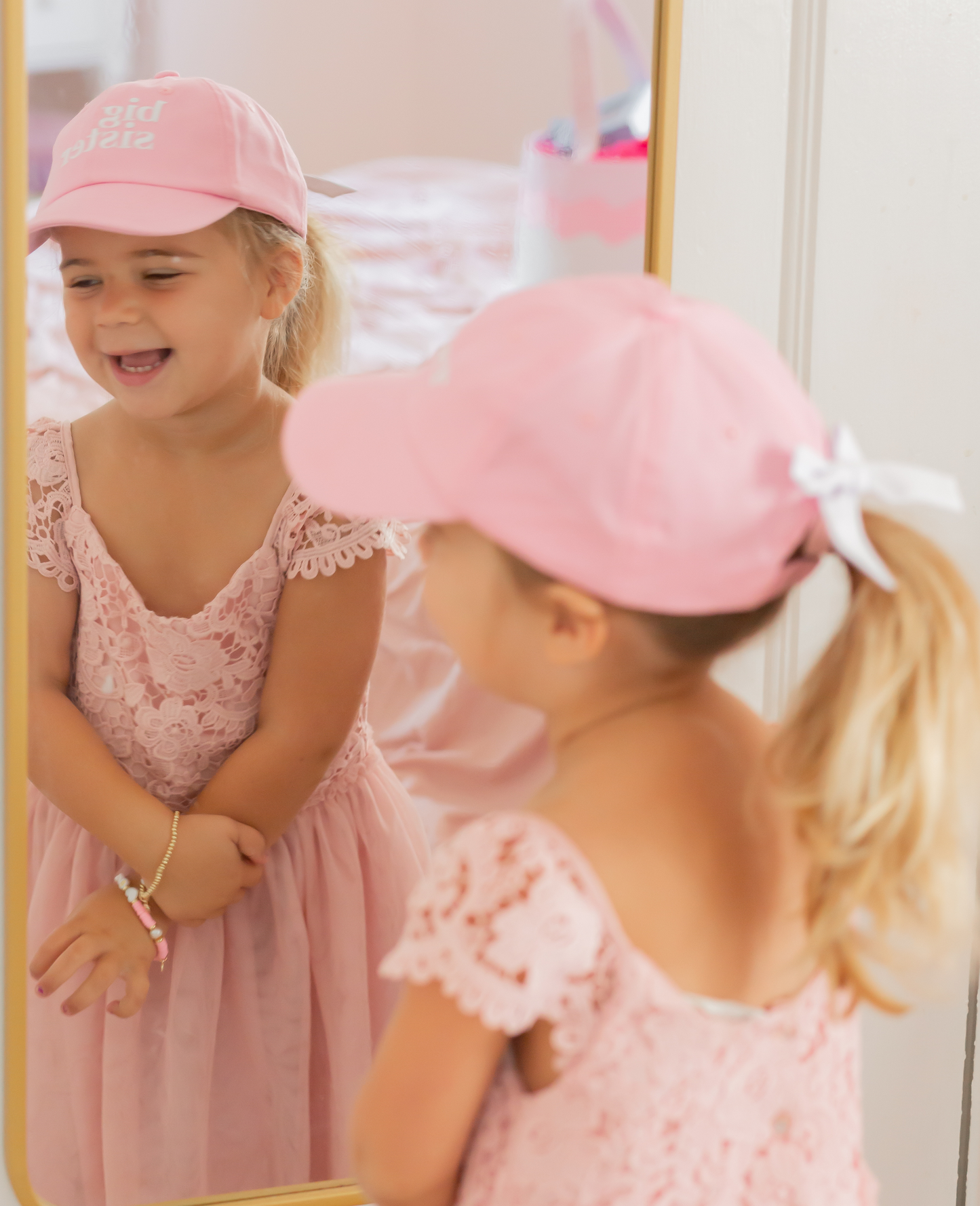 Girl wearing a pink baseball hat with Big Sister embroidery and bow on the back