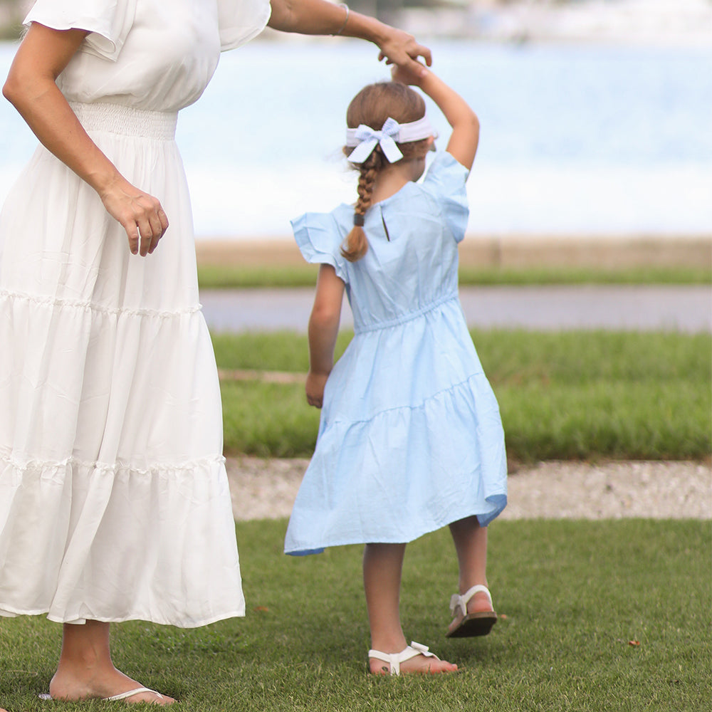 Little girl wearing a white visor with a blue bow on the back