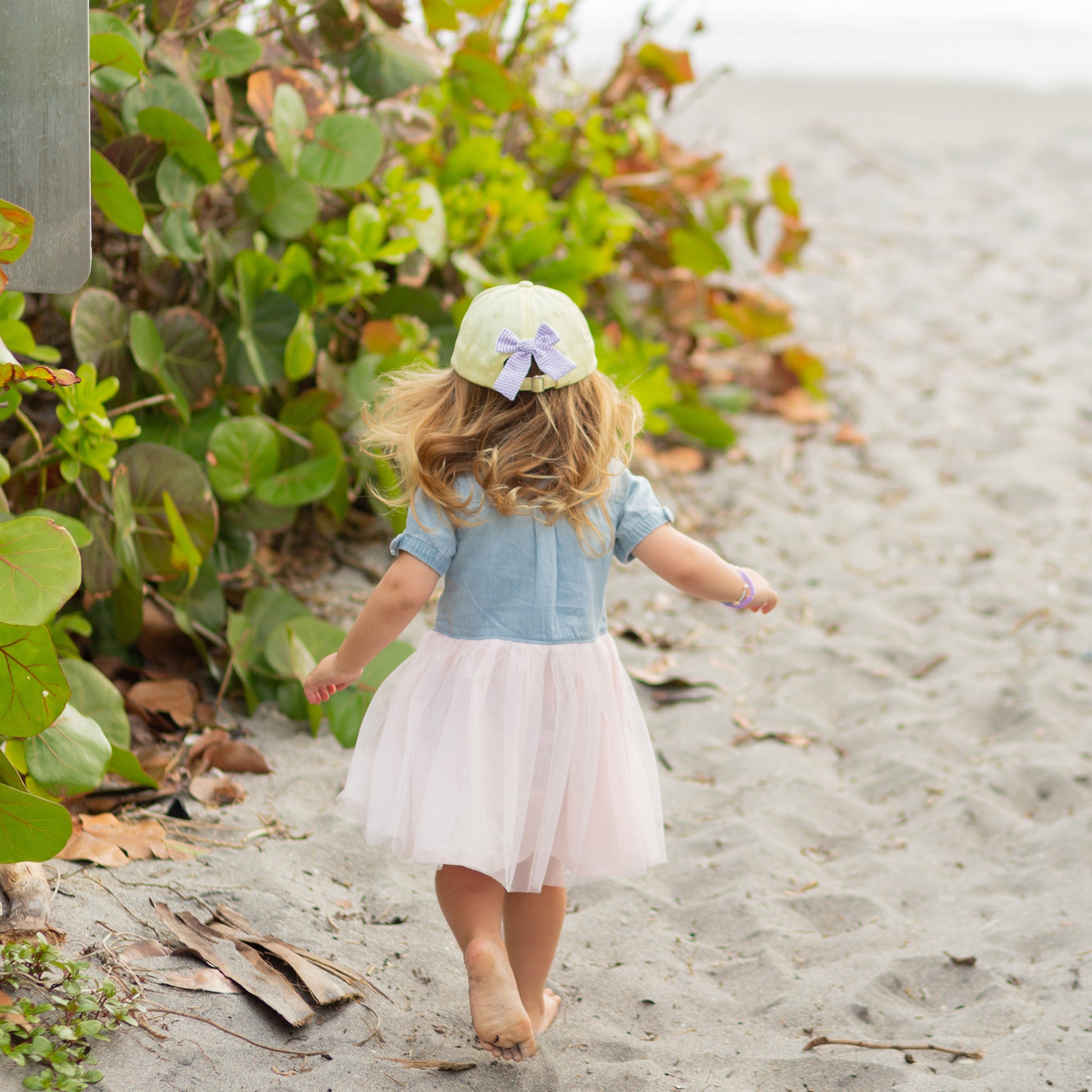 Girl wearing a yellow baseball hat with bow on the back