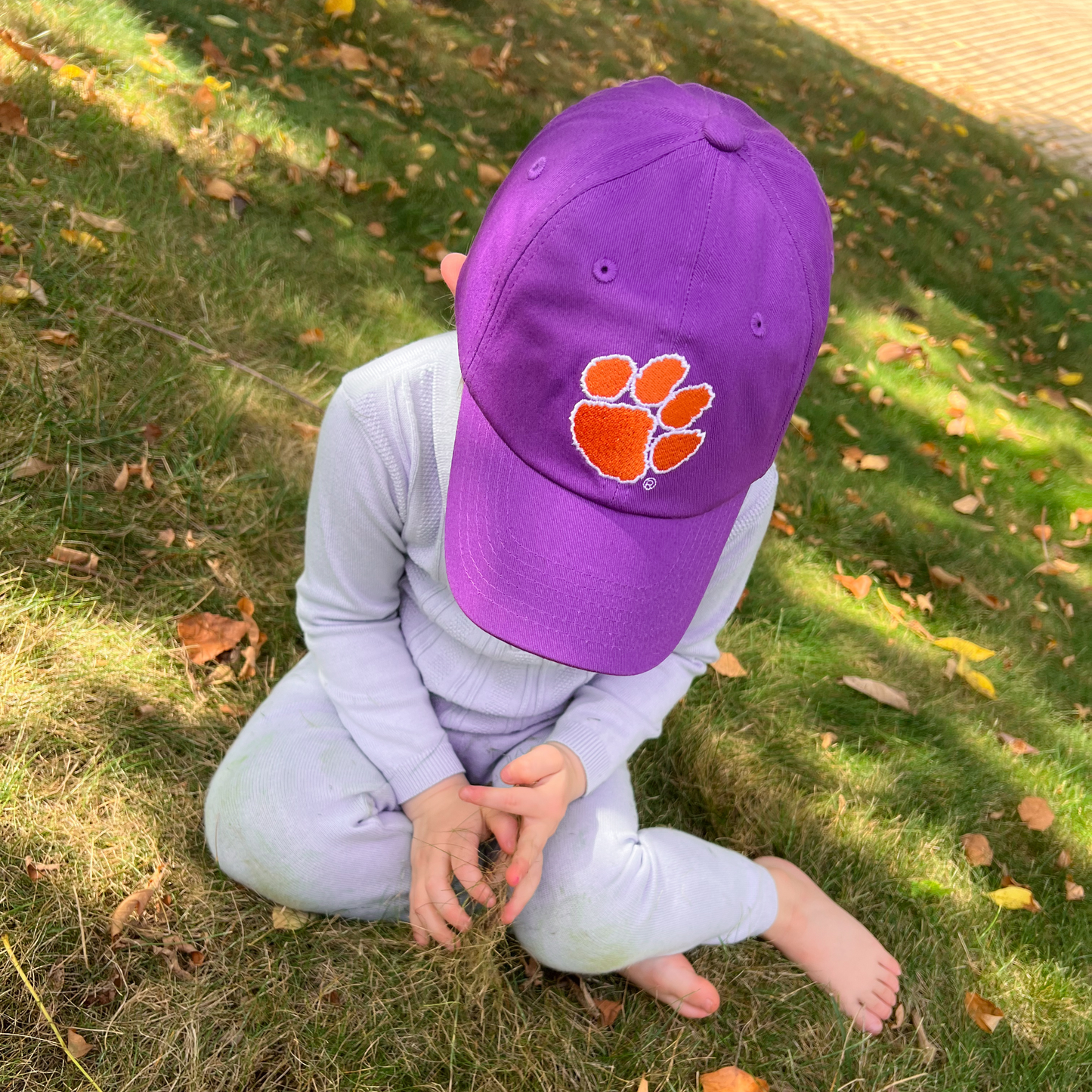 Boy wearing purple baseball hat with Clemson Tigers embroidery