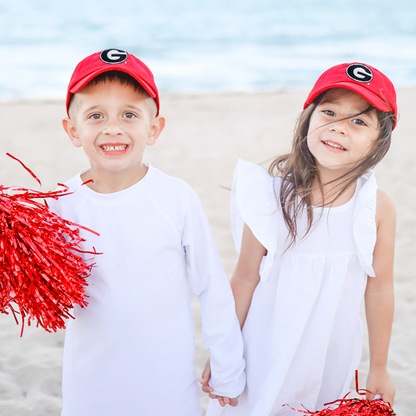 Boy and girl holding hands and wearing red Georgia Bulldogs baseball hats