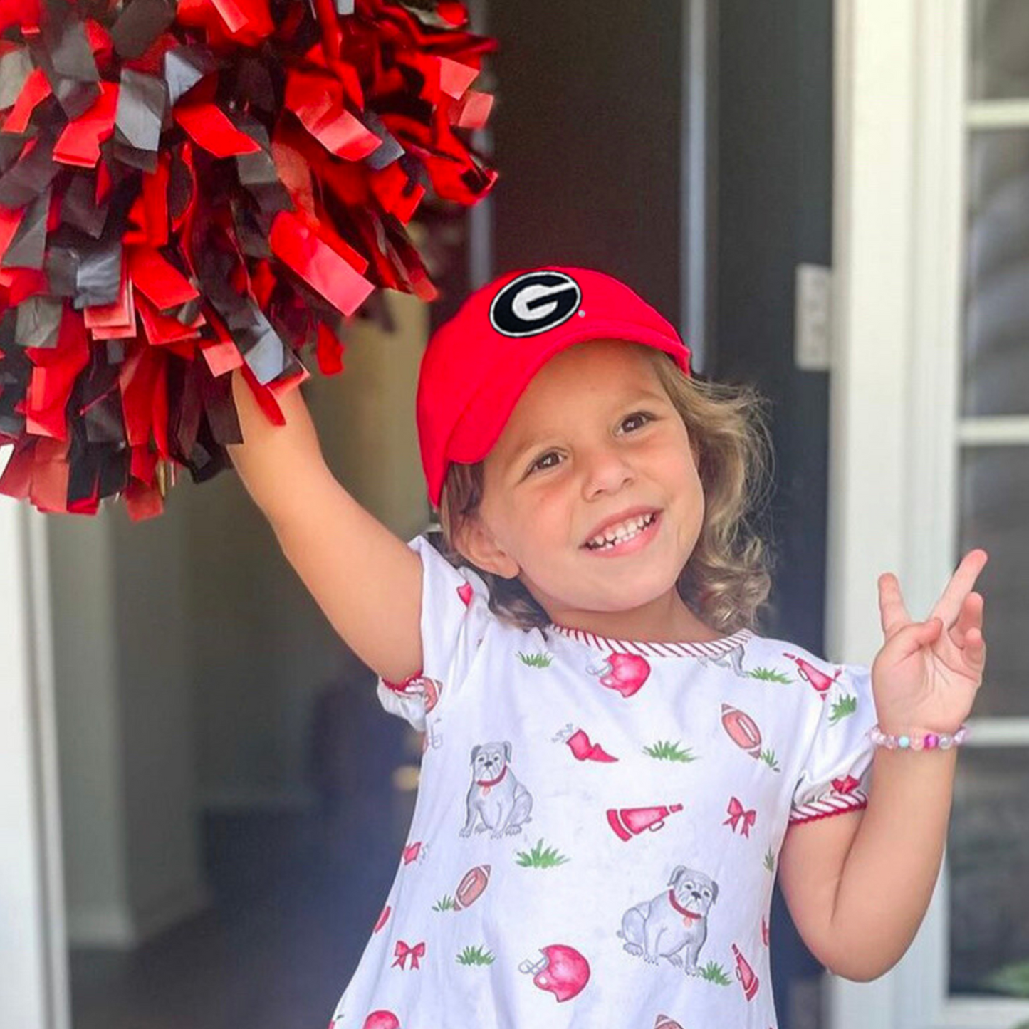 Girl wearing a red Georgia Bulldogs baseball hat with embroidered "G" logo