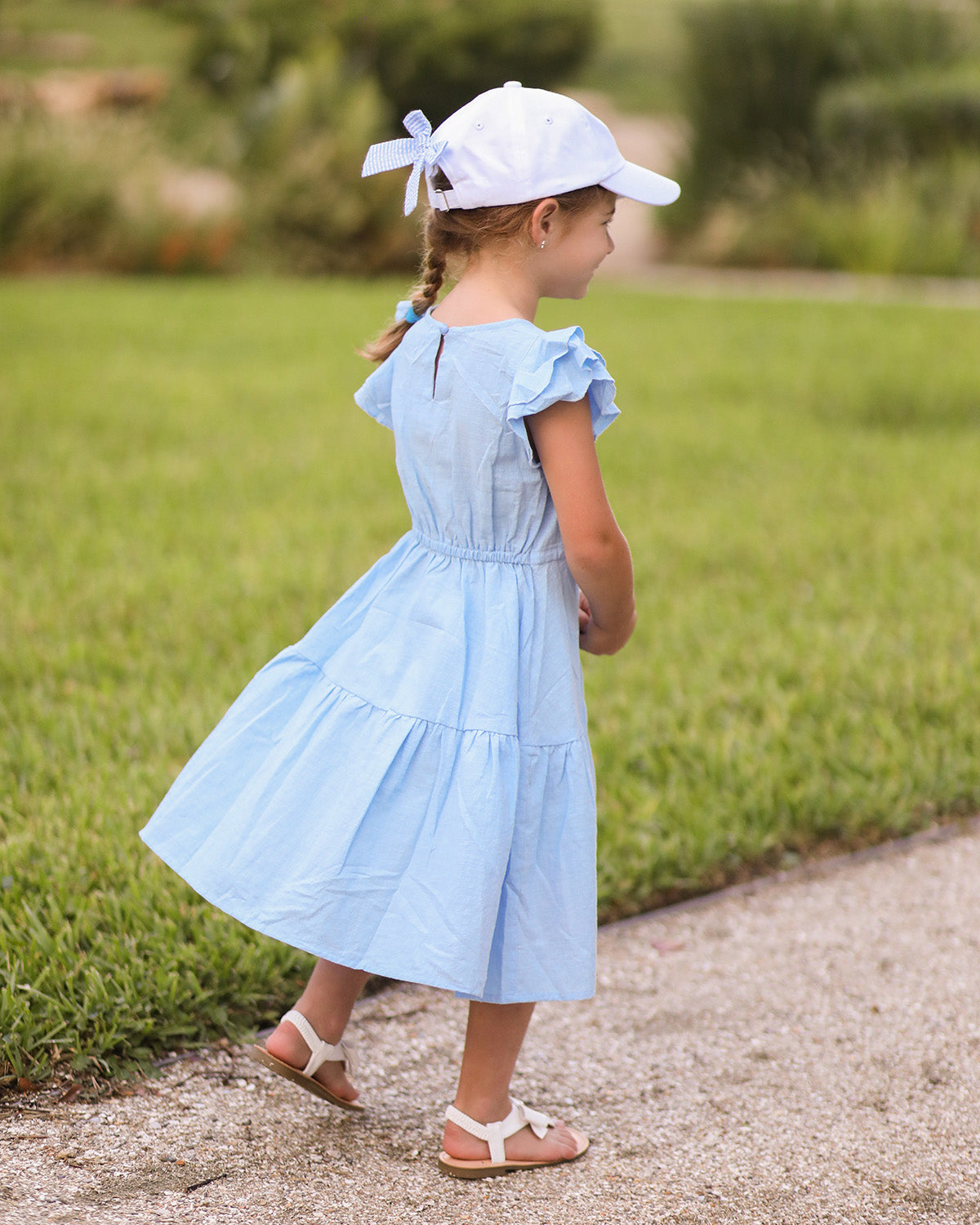 Little girl wearing a white baseball hat with a bow on the back