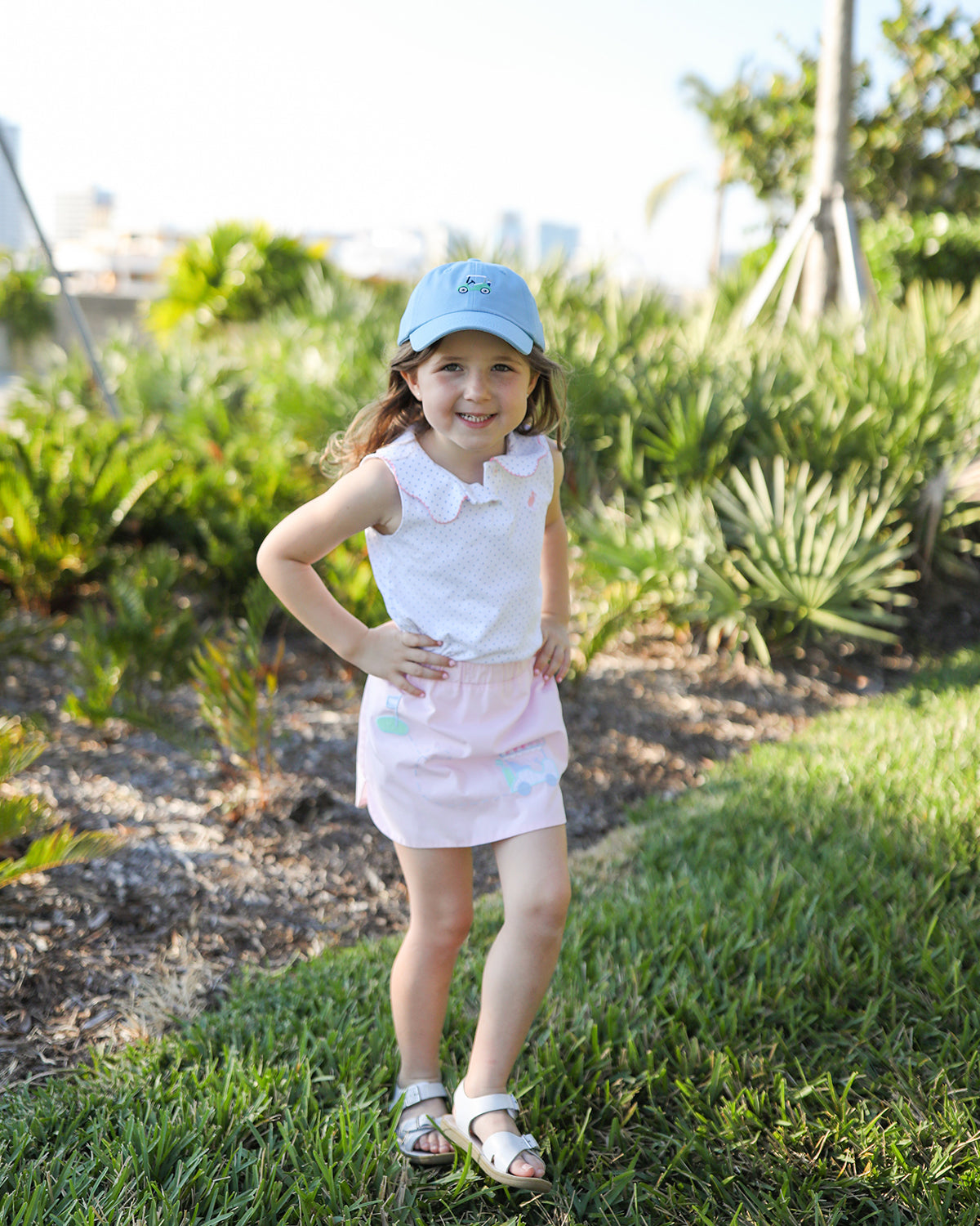 Little girl wearing a blue baseball hat with golf cart embroidery