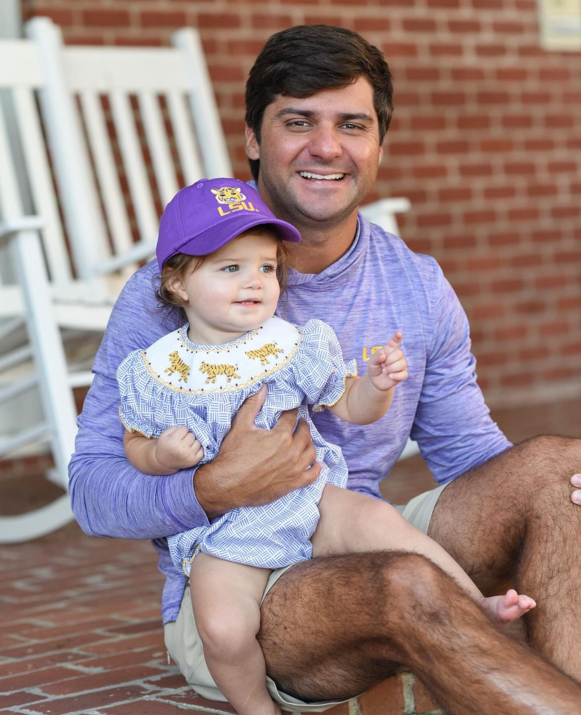 Father with baby girl wearing purple LSU Tigers baseball hat