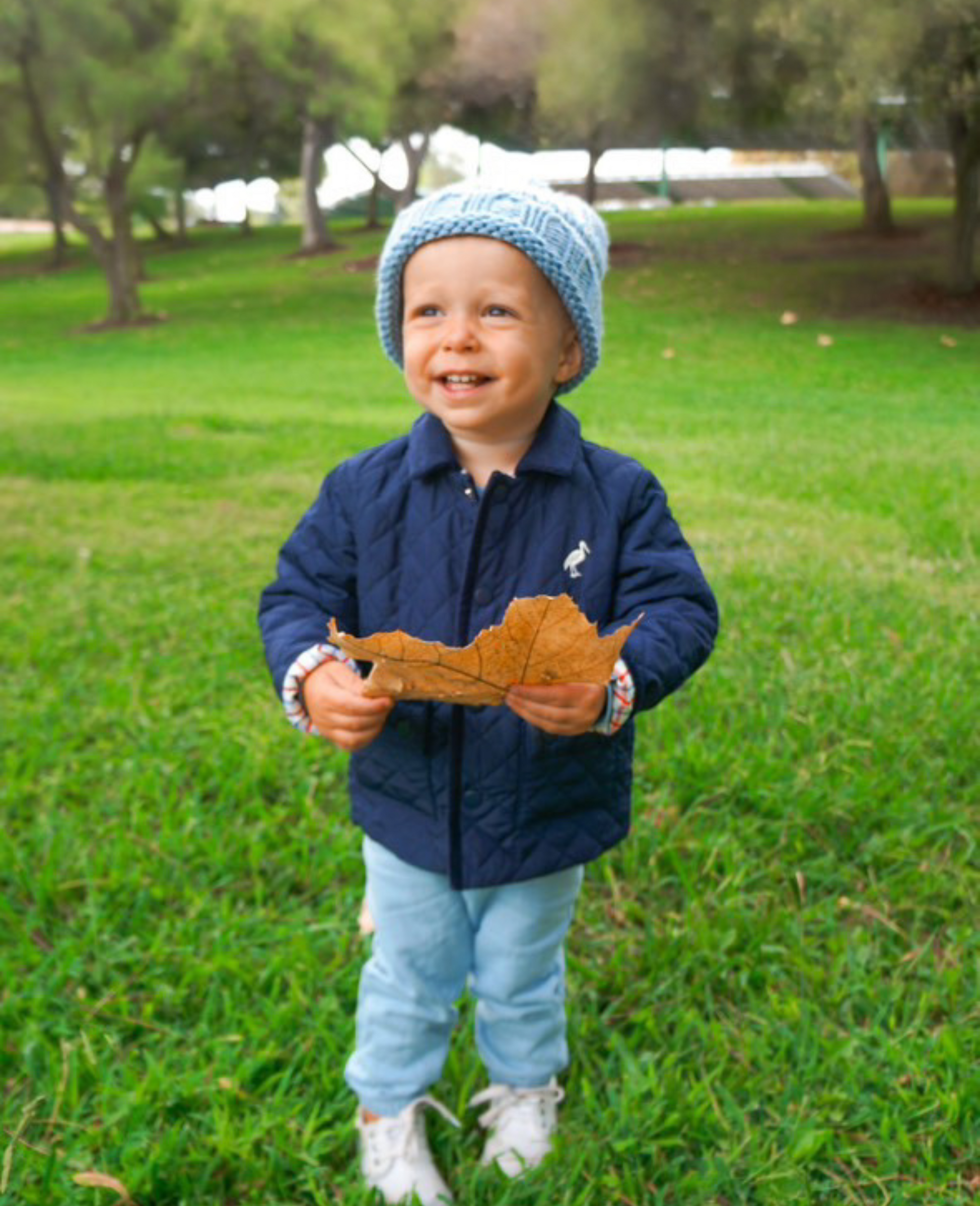 Little boy holding a leaf and wearing a blue bobble hat