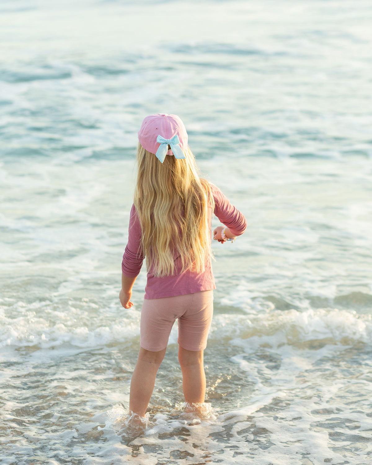 Girl wearing a pink baseball hat with a bow on the back