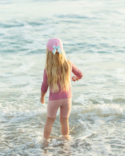 Girl wearing a pink baseball hat with a bow on the back