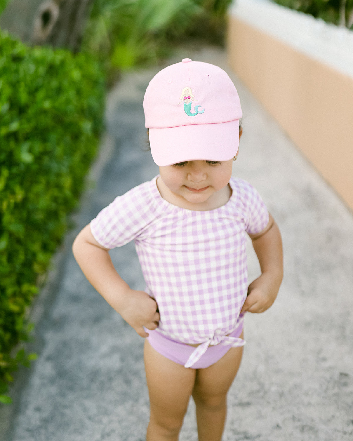 Little girl wearing a pink baseball hat with mermaid embroidery