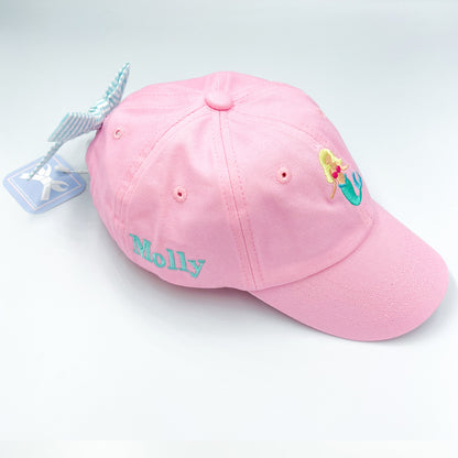 Pink baseball hat with mermaid embroidery on the front, a bow on the back and a name embroidered on the side