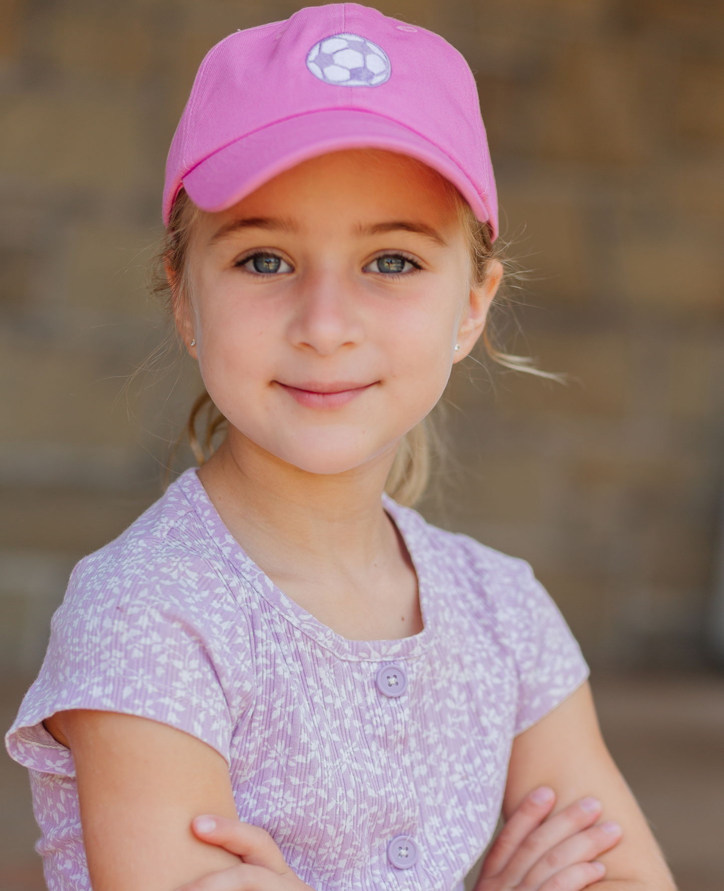 Girl wearing pink baseball hat with soccer ball embroidery