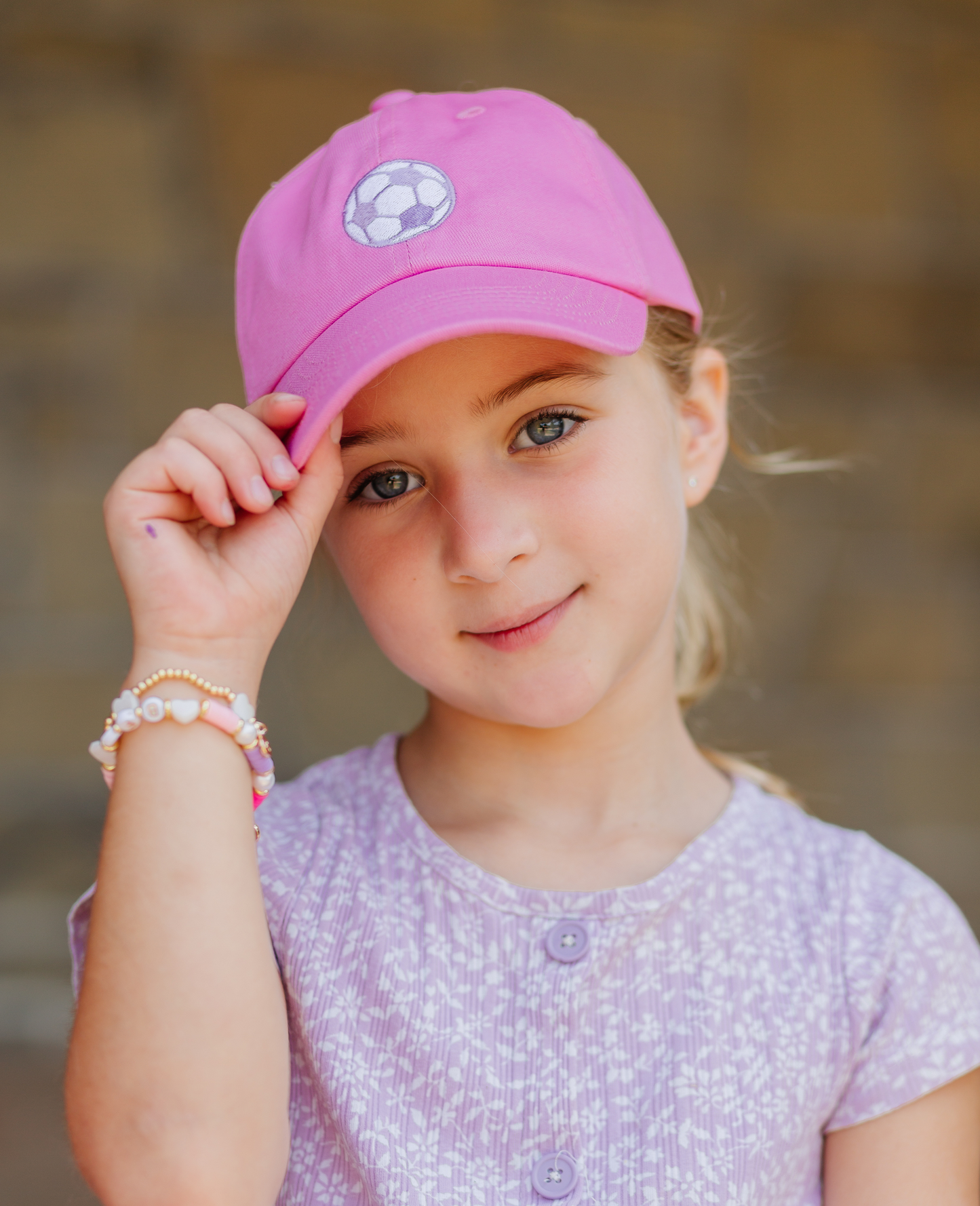 Girl wearing pink baseball hat with soccer ball embroidery