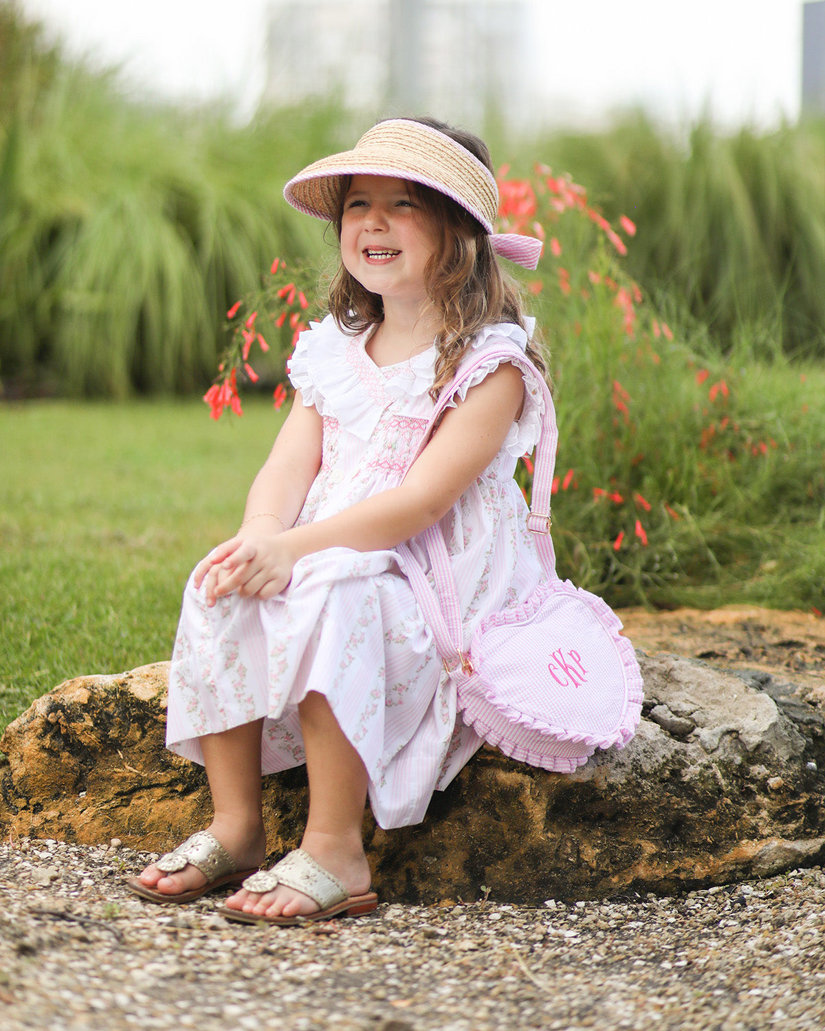 Little girl wearing a straw visor with pink and white seersucker bow on the back