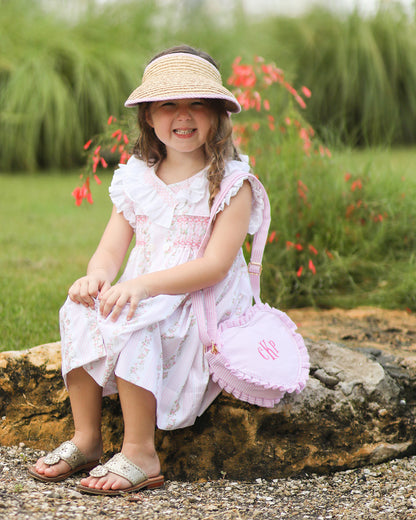 Little girl wearing a straw visor with pink and white seersucker bow on the back