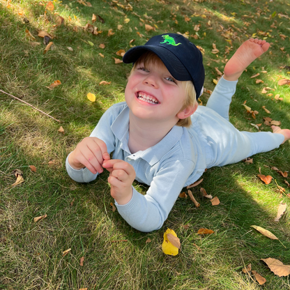 Boy wearing a navy blue baseball hat with t-rex motif embroidery