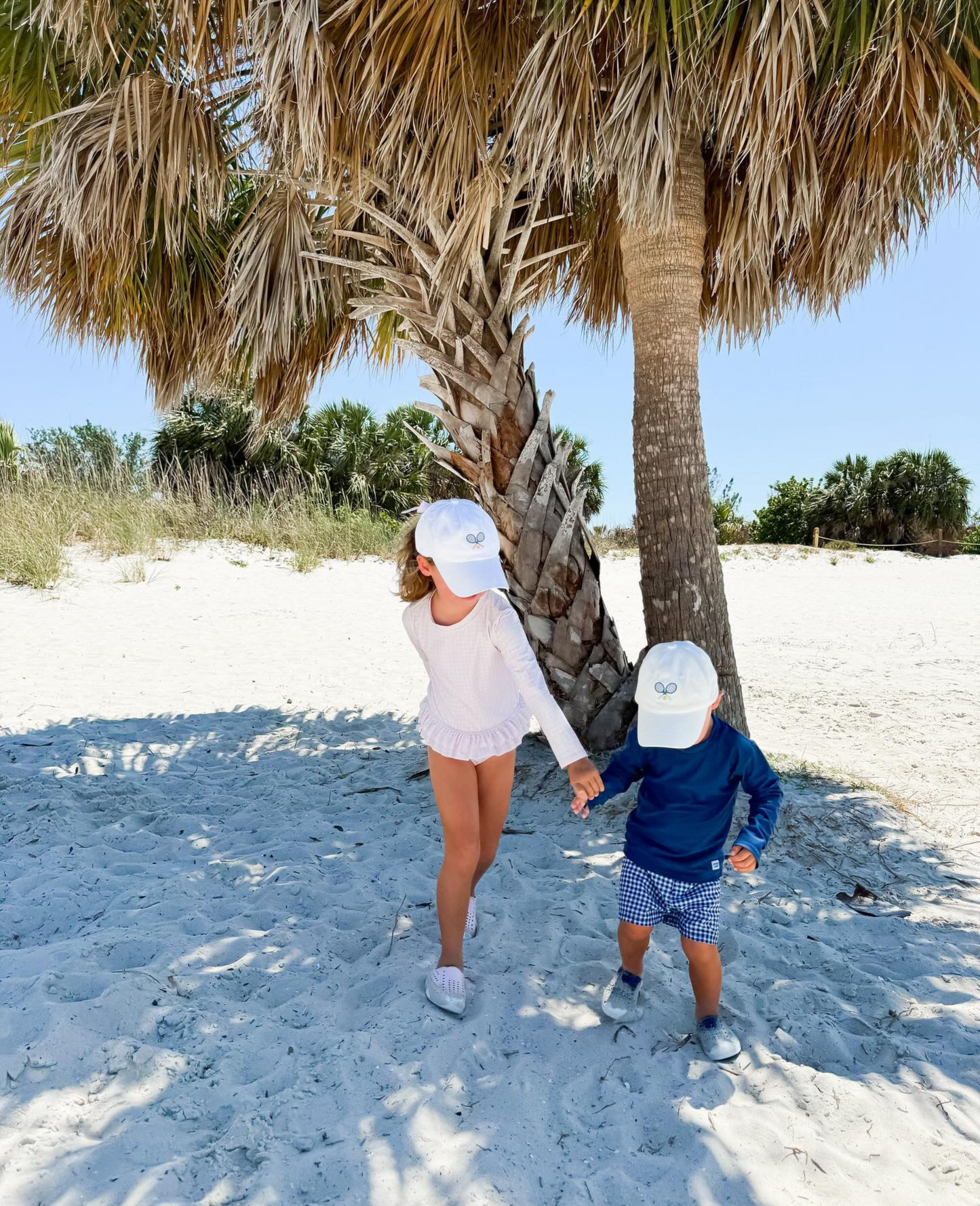 Kids wearing matching baseball hats with tennis embroidery