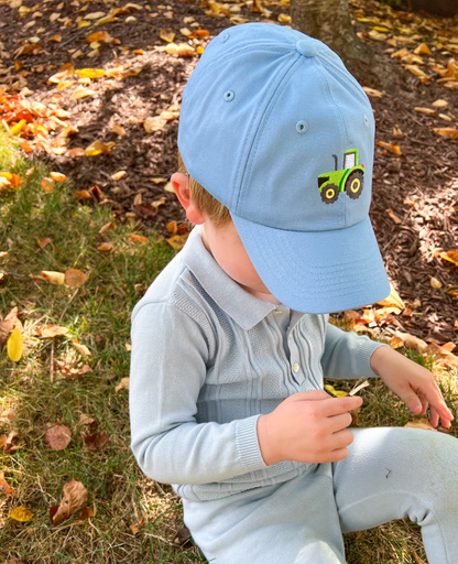 Boy wearing a blue baseball hat with   tractor motif embroidery